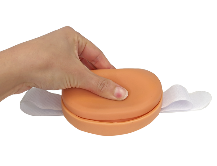 A hand holds an orange, cushioned medical device with a white strap. The device is being positioned. The background is plain white.