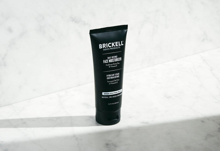 Brickell Men's Products Daily Defense Face Moisturizer SPF 20 tube on marble surface