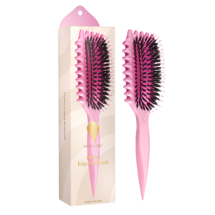 Pink hairbrush with black bristles next to its packaging on a white background