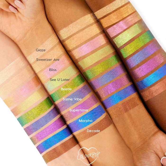 Feelin’ Bold ColourPop Chrome Liquid Shadow swatches gleam on four forearms, showing multi‑chrome shifts from gold, pink, lime, and teal to blue and copper; shade names like Glaze, Beetle, Morpho, and Decode appear beside each stripe for comparison.