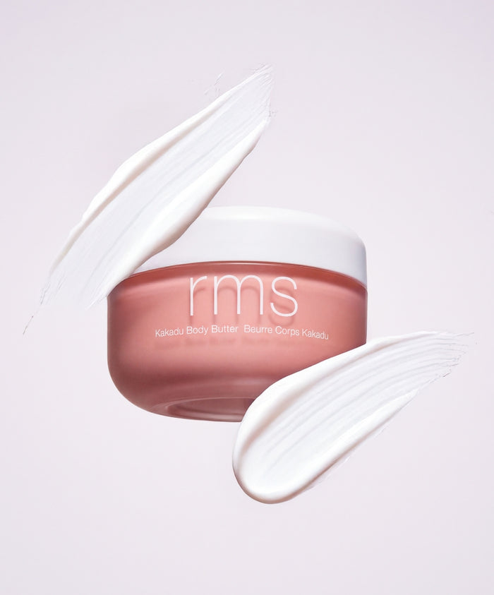 RMS Beauty Kakadu Body Butter in a pink jar with white lid surrounded by creamy white swatches, showcasing clean beauty and natural skincare ingredients.