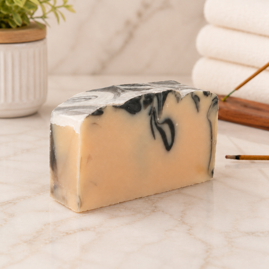 Marble-patterned goat milk soap bar on a marble surface with a blurred background