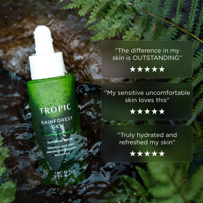 Tropic Rainforest Dew hydration serum bottle in flowing water surrounded by ferns, with customer review quotes and five-star ratings displayed beside it.