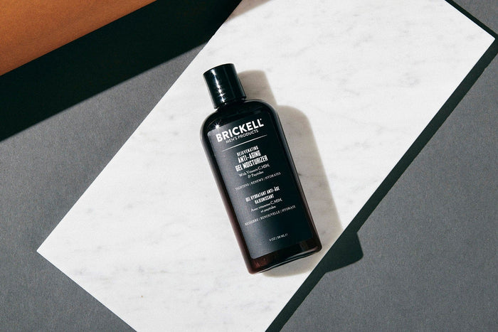 Brickell men's anti-aging gel moisturizer bottle on white marble slab with grey background