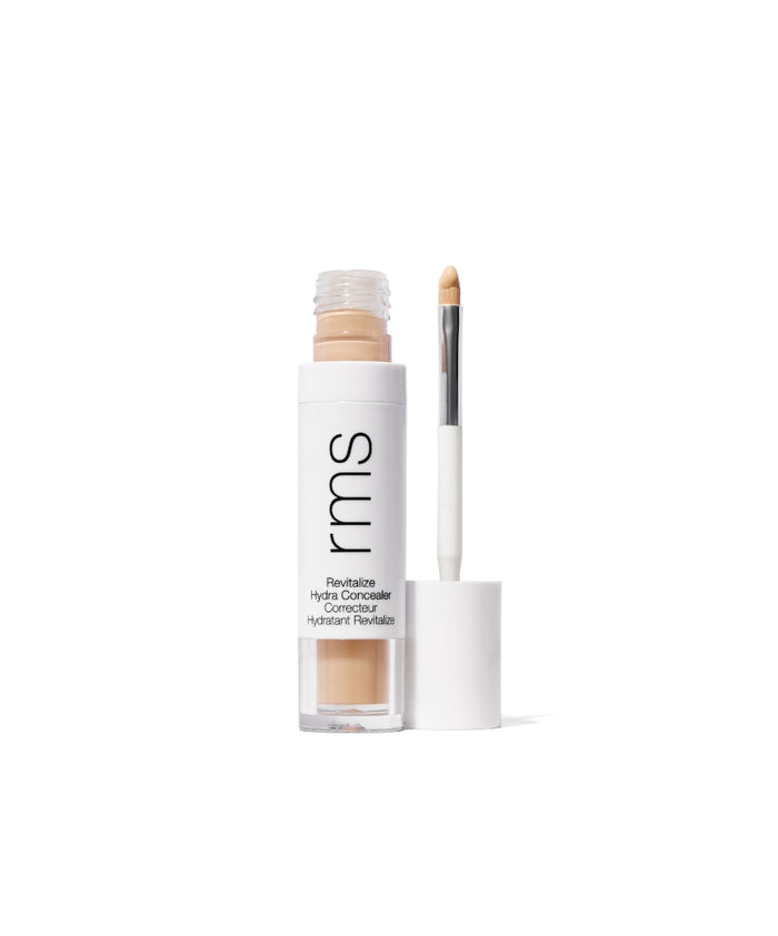 Open tube of Revitalize Hydra Concealer showing a light beige creamy formula and attached applicator wand with a white and clear sleek packaging design.