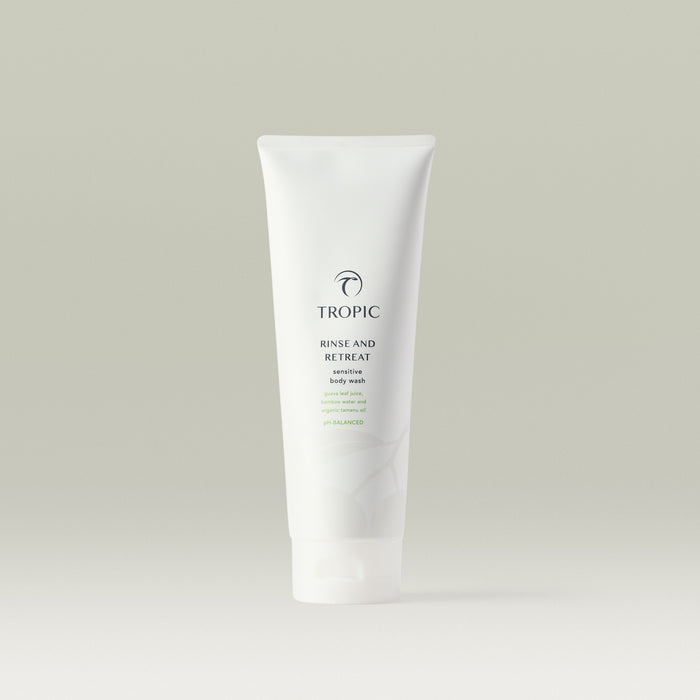 Tropic Rinse and Retreat Sensitive Body Wash in a sleek white tube with minimalist green accents, featuring guava leaf juice, bamboo water, and organic tamanu oil.