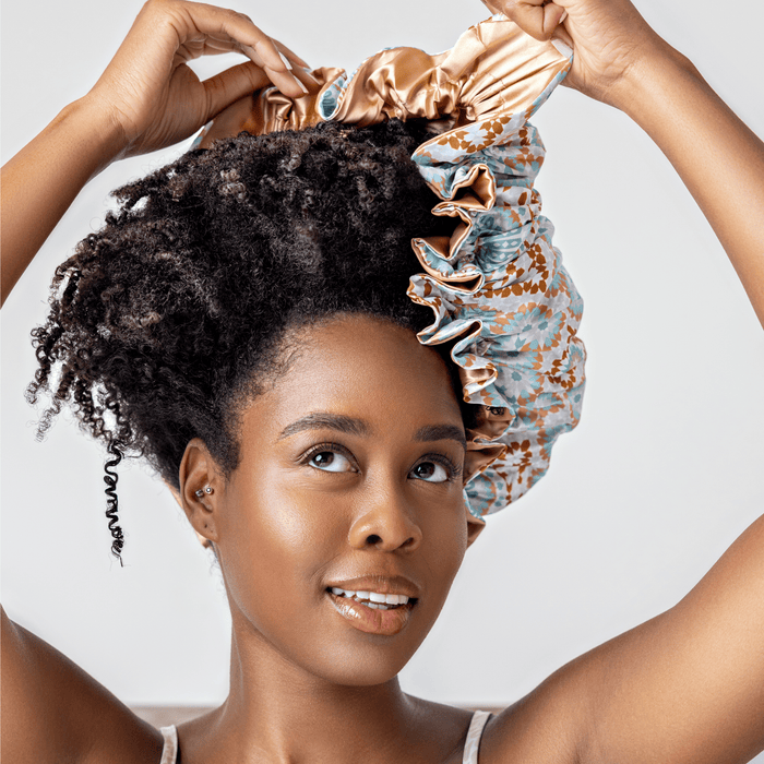 A woman with coily hair wearing a Bounce Curl satin bonnet, a comfortable curly hair accessory.