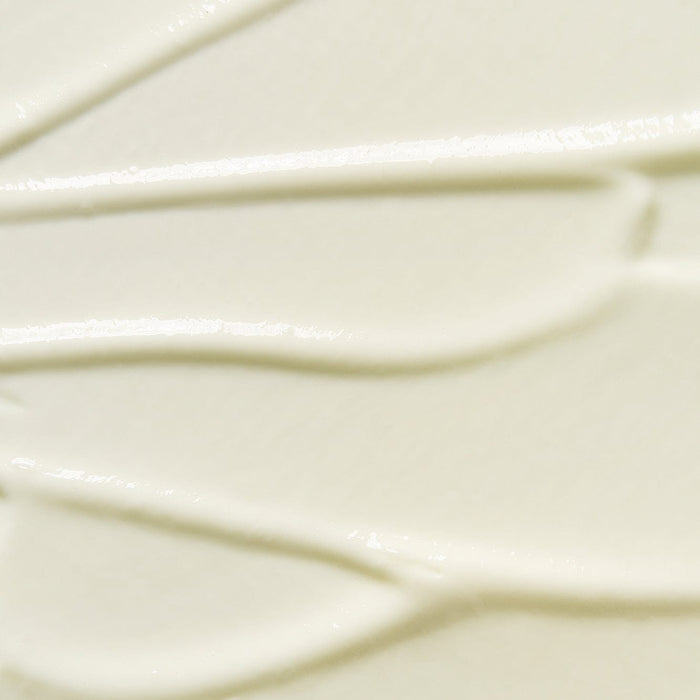 Close-up texture of Tropic Sun Day dewy facial SPF 50 sunscreen, showing smooth creamy consistency with subtle swirls.